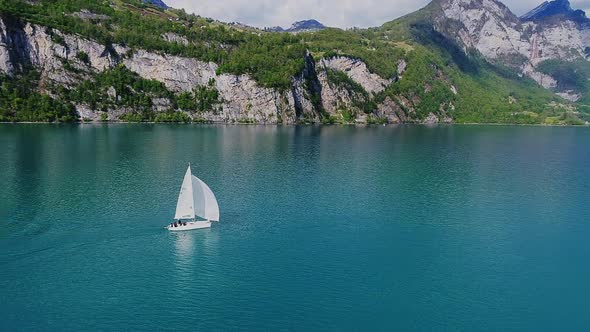 Aerial video of a sail boat cruising along Walensee Lake in Switzerland during Summer (2)