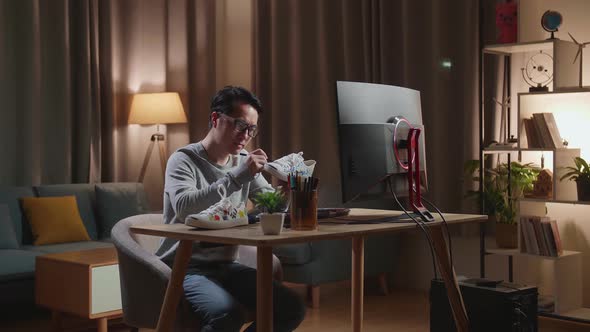 Asian Male Footwear Designer With A Desktop Computer Putting Coloured Unique Patterns On Sneakers