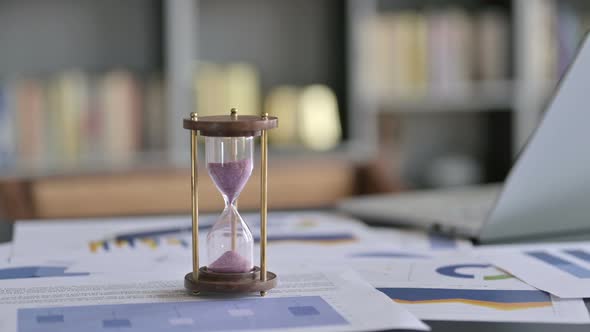 Close Up of Hourglass on Office Desk with Document