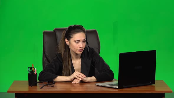 Business Woman in Headphones Speaking By Webcam and Look at Laptop. Green Screen. Slow Motion