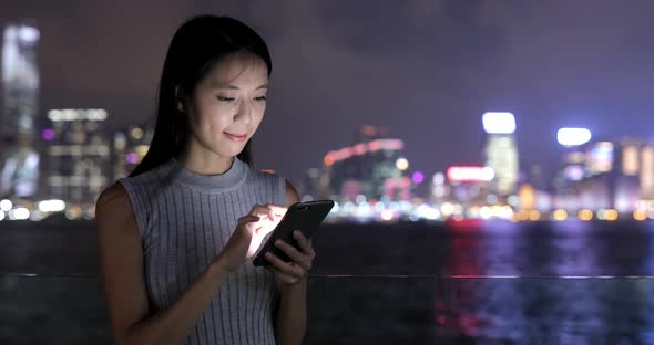 Woman using smart phone in city at night 