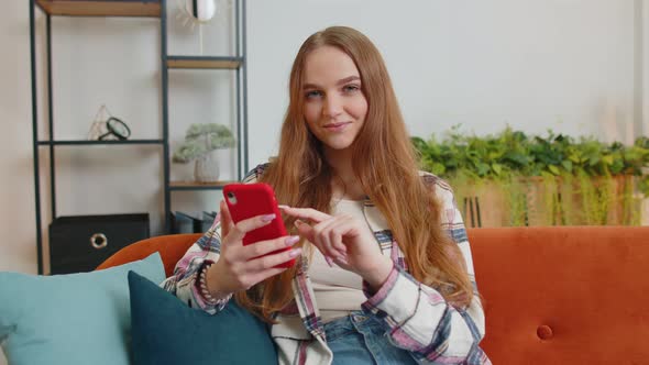 Joyful Young Adult Woman Sitting on Sofa Using Smartphone Watching Video Online Shopping Tapping