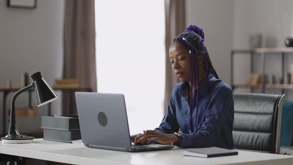 Pretty Black Woman is Working Remotely From Home Sitting at Table and Sending Message By Laptop