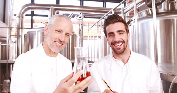 Two Men in Lab Coat Looking at the Beaker with Beer