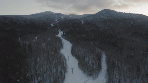 Flying above an abandoned ski lift towards the peak of a snow frosted mountain AERIAL