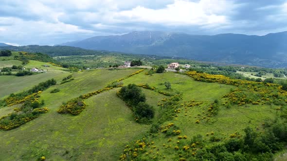 Aerial shot of a vast mountain landscape with a house and a motorcycle passing