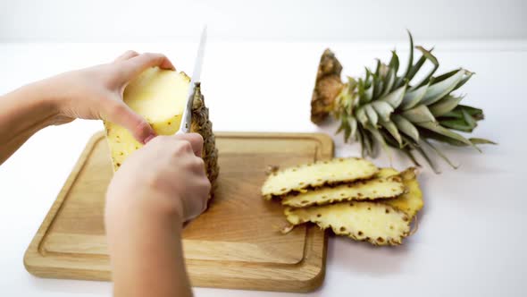 Peeling pineapple on a cutting board. 