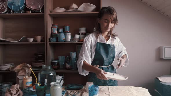 Professional Potter Decorating and Painting a Dish After She Has Baked It in the Kiln