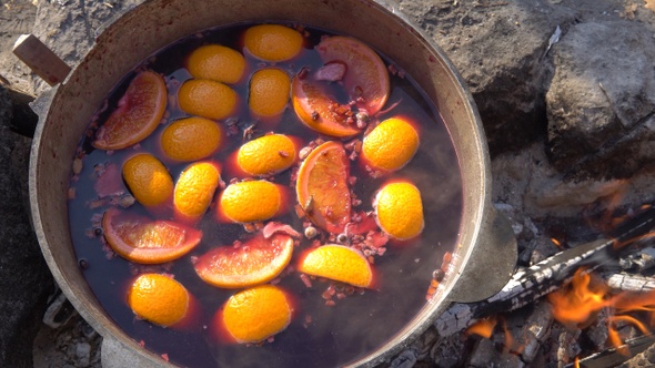 Cauldron with a stewed fruit is heated on the bonfire at the campsite