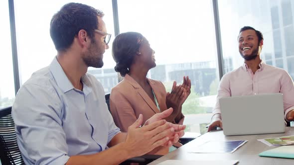 Businesspeople interacting and applauding a coworker