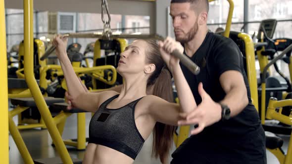 Young Woman with Instructor Working Out in Gym