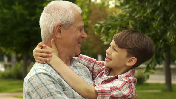 Little Boy Holds His Hands Behind His Grandpa's Neck