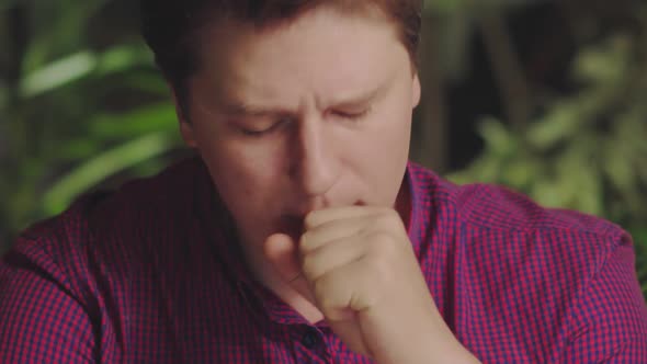 Young Man Coughs While Sitting at the Computer