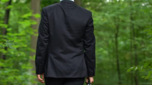 Office Worker Walking in Forest With Briefcase, Turning Round and Breathing Deep