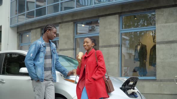 African American Couple Stands Groceries Near Electric Car