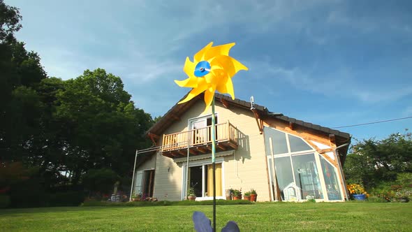 Yellow windmill spinning in wind in front of wooden house