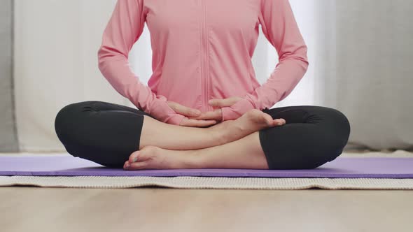 Close-up hands a beautiful Asian female practicing yoga meditating in a lotus position at home.