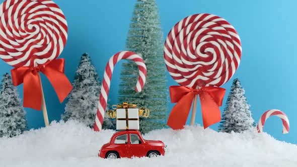 Red Santa Car with in Christmas Tree Forest with Candies and Lollipops Sweets. Merry Christmas and