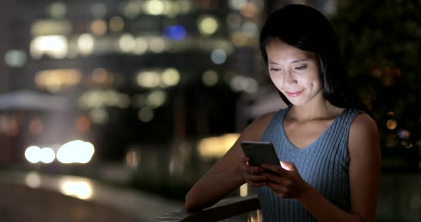 Businesswoman Looking at Mobile Phone in The City at Night 