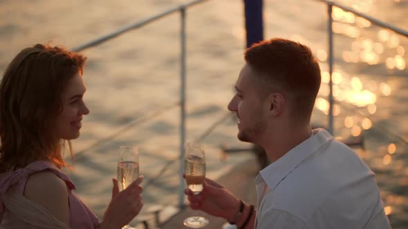 Young Happy Man and Woman Clinking with Glasses of Sparkling Wine While Yachting in Open Sea on