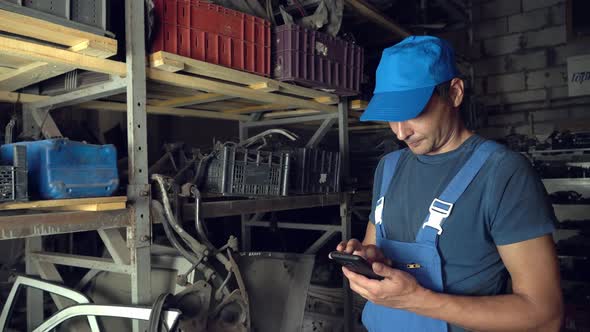 employee of auto disassembly, completes or checks car parts from tablet computer