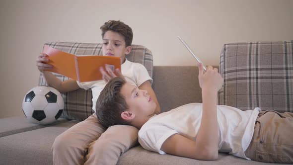 Two Caucasian Schoolboys Resting at Home on the Sofa