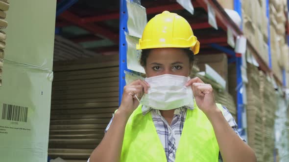 Portrait African American woman worker with safety vest, hard helmet wear face mask look at camera.