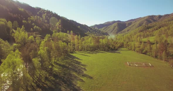 Mid Air Flight Over Fresh Mountain River and Meadow at Sunny Summer Morning. Rural Dirt Road Below
