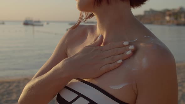 Woman Applying Sunscreen on Her Neck Standing on the Beach