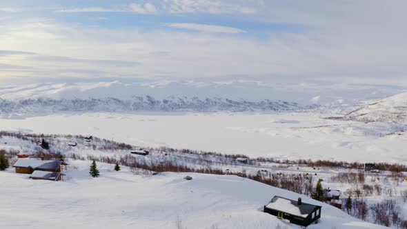 Mountainside Cabins And Snow Covered Mountains In Huagastol Norway - Aerial shot