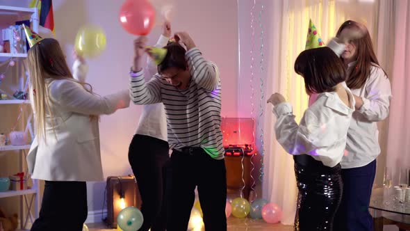 Joyful Millennial Men and Women Fighting with Balloons at Birthday Party