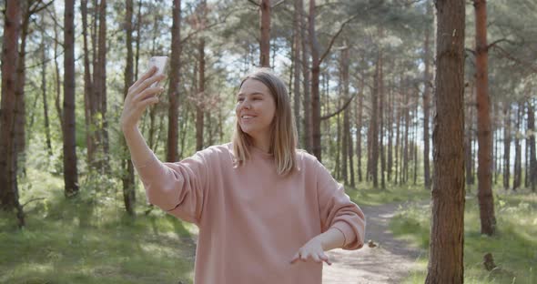 Young Attractive Woman Making Video Call on a Smartphone in a Summer Forest