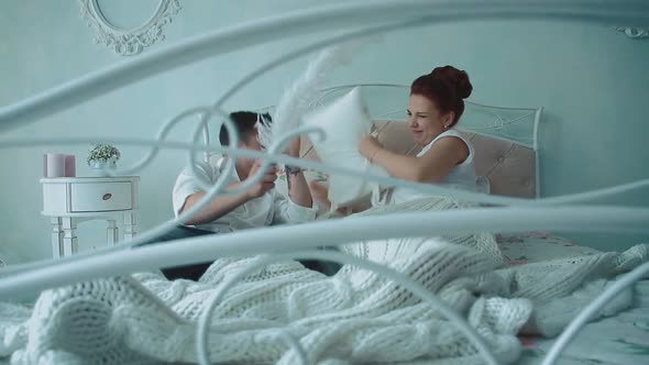 Young Beautiful Couple Having Fun in Bed, They Fight By Cushions, Passing Camera Along the Bed, Slow