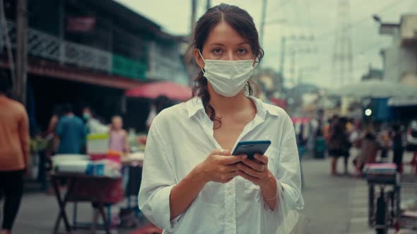 Portrait of a Young Woman Typing on a Smartphone in the Street