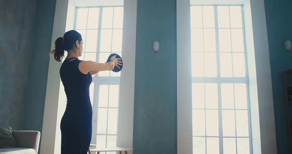 Woman Does Sports Exercises with Weight Plate at Home