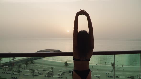 Girl in a Swimsuit Raises Her Hands Up