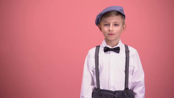 Little Boy in Vintage Clothes Looking Into Camera, Isolated on Pink Background