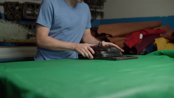 Craftsman Laying Out Steel Punch Knife Moulds on Leather Sheet Indoors