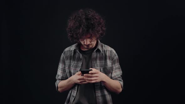 The Charismatic Young Man Seriously Types a Message on the Phone