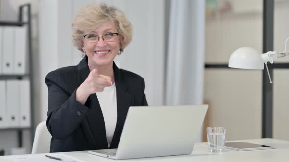 Old Businesswoman with Laptop Pointing at the Camera