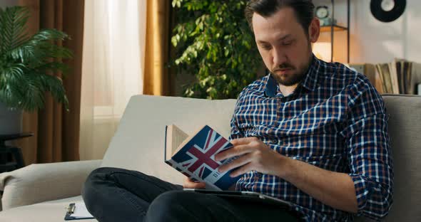 The Man is Sitting on Couch at Home Doing Homework for Extra English Classes Learning to Form