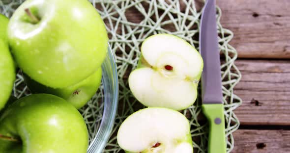 Green apples and knife on wooden plank