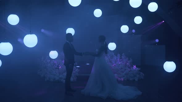 The Bride and Groom Dance the First Dance on Stage Around Them Laser Projection and Many White Balls