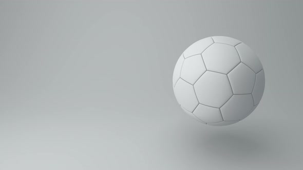 White Soccer Ball Rotate Around its Axis in a Gray Studio. Monochrome.