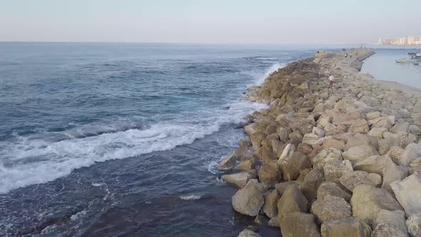 Deep blue waters of the Mediterranean gently roll over the breakwater while Jaffa and Tel Aviv sunse