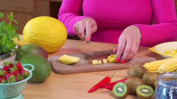 Woman in a Pink Blouse Chopping a Juicy Yellow Mango 