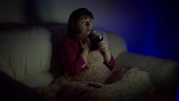 Woman on the Couch with a Glass of Wine Watching an Exciting Movie on the Tv, Worries