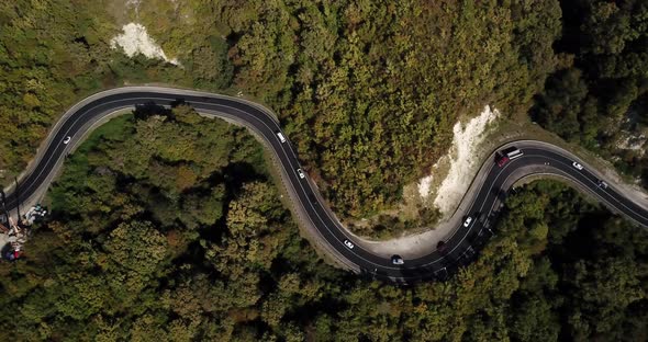 Aerial View of Car Driving Along The Winding Mountain Pass Road Through The Forest Trees. Autumn