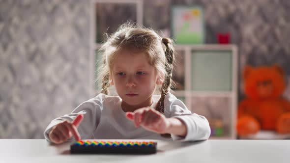 Upset Little Girl Plays with Abacus at Mental Arithmetics