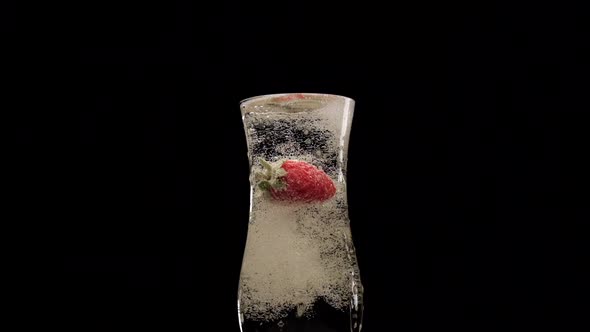 Strawberry in champagne flute at slow motion. Fruit berry splashing in wine prosecco alcohol drink o